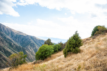 Majestic mountains of Armenia under a blue sky filled with clouds, showcasing natural beauty and rugged terrainの写真素材