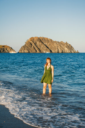 Carefree beautiful redhead woman enjoys summer waves near a scenic tropical beachの写真素材
