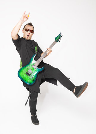 Stylish emotionally musician standing and moving with a green electric guitar and confident modern aestheticの写真素材