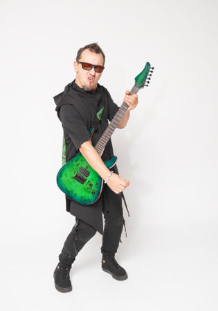 Stylish emotionally musician standing and moving with a green electric guitar and confident modern aestheticの写真素材