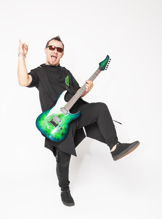Stylish emotionally musician standing and moving with a green electric guitar and confident modern aestheticの写真素材