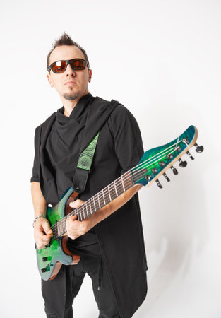 Stylish musician standing and posing with a green electric guitar and confident modern aestheticの写真素材