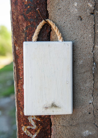 Old white wooden blank signboard on the old aged cement and metal wall backgroundの写真素材