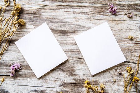 Minimalist mockup featuring a two blank white postcards on a wooden table with dried flowersの素材