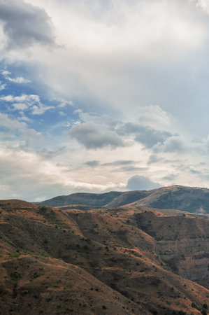 Majestic mountains of Armenia under a blue sky filled with clouds, showcasing natural beauty and rugged terrainの写真素材
