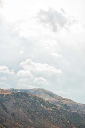 Majestic mountains of Armenia under a blue sky filled with clouds, showcasing natural beauty and rugged terrainの写真素材