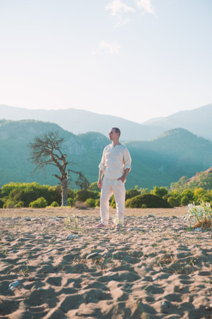 Man meditates barefoot in a vast desert landscape surrounded by mountains. Serene and tranquil environment perfect for self-reflectionの写真素材