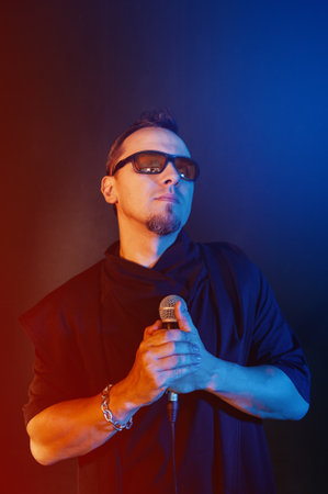 Rock singer man with microphone and sunglasses against red and blue backgroundの写真素材