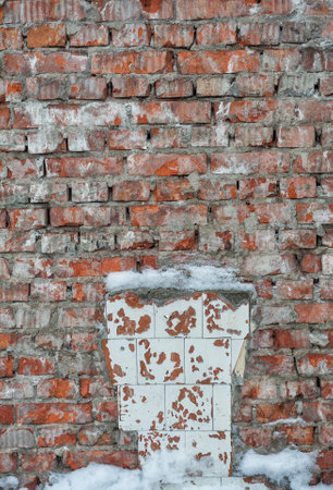 Weathered textures of rustic brick wall with snow in winterの写真素材