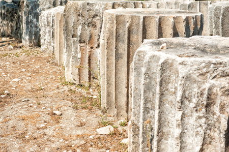 Ancient stone columns with weathered surfaces stand in ruins. Archaeological remains a showcase of classical architecture from past civilizations. Eroded relics highlight historical heritage in a dry landscapeの写真素材