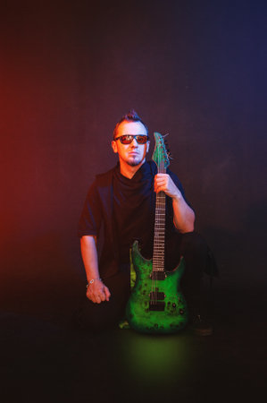 Musician rock guitarist plays green electric guitar sits against red and blue backgroundの写真素材