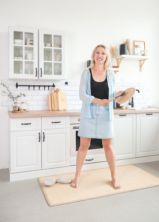Woman stands in a modern stylish kitchen with an expressionの写真素材