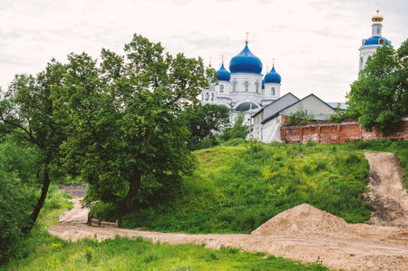 Winding rural road leads to orthodox church with iconic blue domes rises above lush Russian countrysideの写真素材