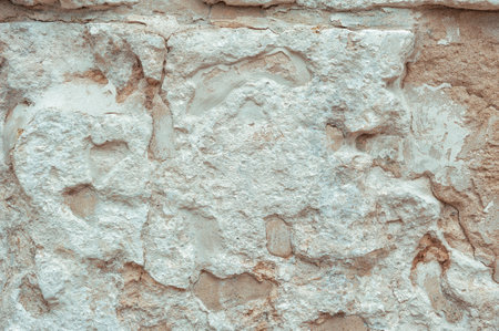 Rustic surface of weathered stone wall with rough texture and sandy tones