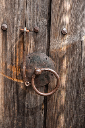 Rustic wooden door with an antique iron handle shows weathered texturesの写真素材
