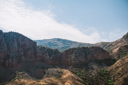 Majestic mountains of Armenia under a blue sky filled with clouds, showcasing natural beauty and rugged terrainの写真素材