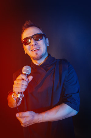 Rock singer man sings and screams with microphone and sunglasses against red and blue backgroundの写真素材