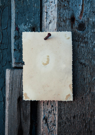Old vintage paper hanging on aged wooden wall nailed by rusty nailの写真素材