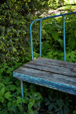Vintage weathered blue bench with chipped paint sits in quiet shadeの写真素材