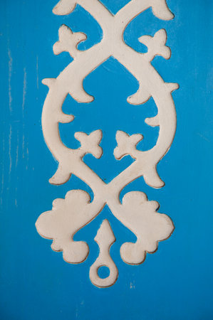 Decorative ethnic carved ornament on blue wood surface showcases vintage artisan detailの写真素材