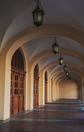 Elegant arched corridor with vintage hanging lanterns. Historic building facade with soft light and...