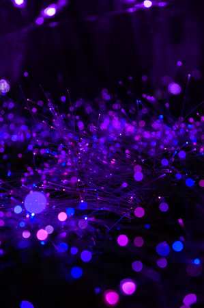 Abstract lights and bokeh form of purple fiber optics glow in a surreal night field creating a...