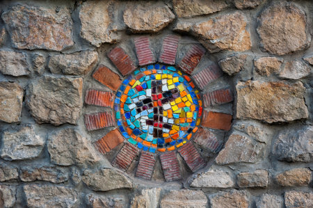 Colorful mosaic embedded in rustic stone wall creates vibrant circular patternの写真素材