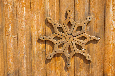 Rustic wooden carving with symmetrical pattern on aged textured plank wallの写真素材