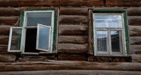 Rustic wooden abandoned house wall with weathered glass windows shows heritage detail