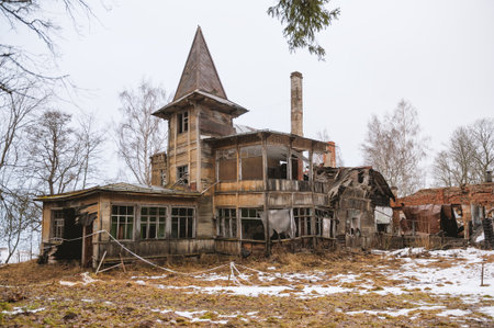 Abandoned wooden house with ruined spire stands in eerie winter landscape