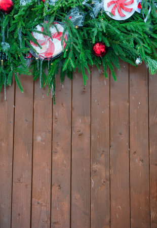 Christmas festive pine garland decorates rustic wooden background with red ornamentsの写真素材