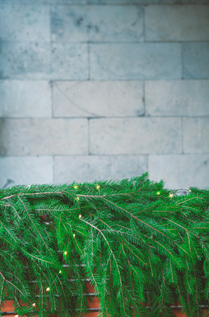 Green pine branches lie under a stone wall creating Christmas natural festive textureの写真素材