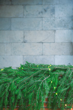 Green pine branches lie under a stone wall creating Christmas natural festive textureの写真素材