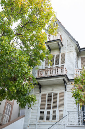 Vintage wooden house with balconies and shutters surrounded by lush greeneryの写真素材