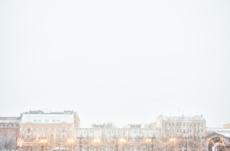 Festive string lights glow against historic city buildings. Urban evening scene captures cozy winter atmosphereの写真素材