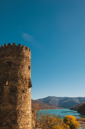 Ancient medieval castle tower overlooks turquoise lake and valley