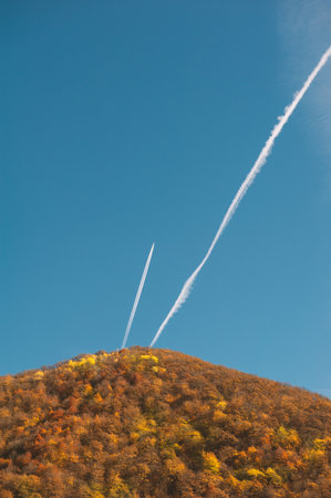 Airplane contrails cut blue sky creating airy dynamic geometry