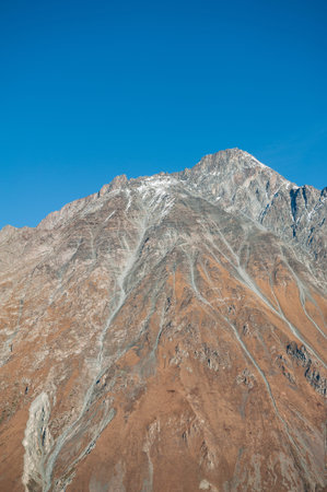 Mountains with snow crowns rise beneath clear sky and bright sunlight