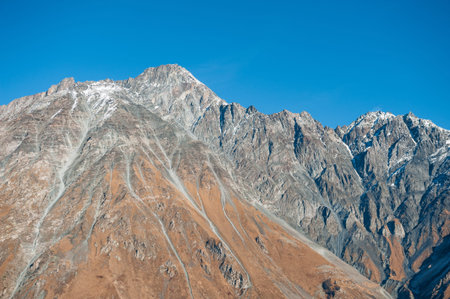Majestic mountains with snow crowns rise beneath clear sky and bright sunlight