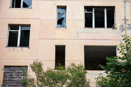 Abandoned building facade with broken windows and peeling plaster.