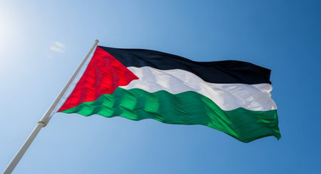The national flag of Palestine waving in the wind against a blue skyの写真素材