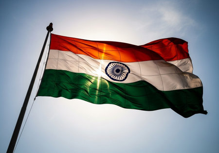 Flag of India waving in the wind against blue sky with sun raysの写真素材