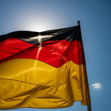German flag waving in the wind with sun and blue sky in backgroundの写真素材