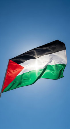 Flag of Palestine waving in the wind on a blue sky background.の写真素材