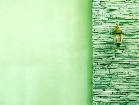Lamp in middle light green ancient stone pieces wall at right and smooth wall at leftの写真素材