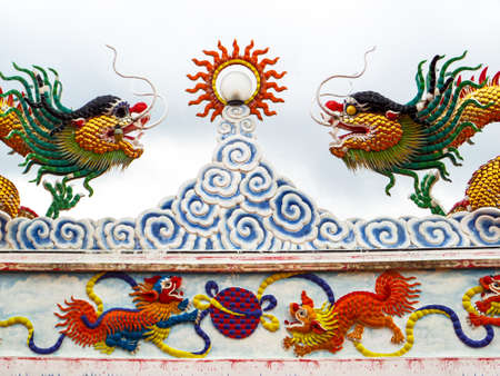 two dragon mosaic on roof and sun beam lantern and gray cloudの写真素材