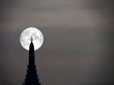 super moon in night sky and silhouette top of ancient pagodaの写真素材
