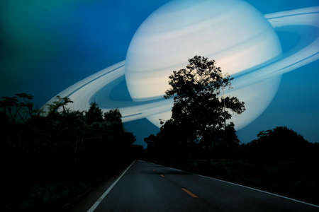 Saturn near earth on night sky over country roadの写真素材