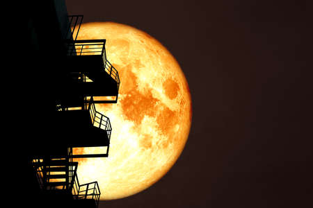 full blood moon over silhouette stair case and colorful sky