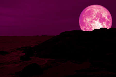 full pink moon back silhouette rock mountain on coastの写真素材
